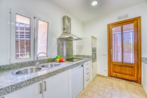 A kitchen with granite countertops, stainless steel sink, and a wooden door. - Finca with pool Son Manyo Gran I Sa Pobla (Sa Pobla)