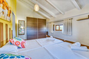 Une chambre à coucher avec un lit, une armoire en bois, une fenêtre avec des rideaux et un luminaire suspendu.