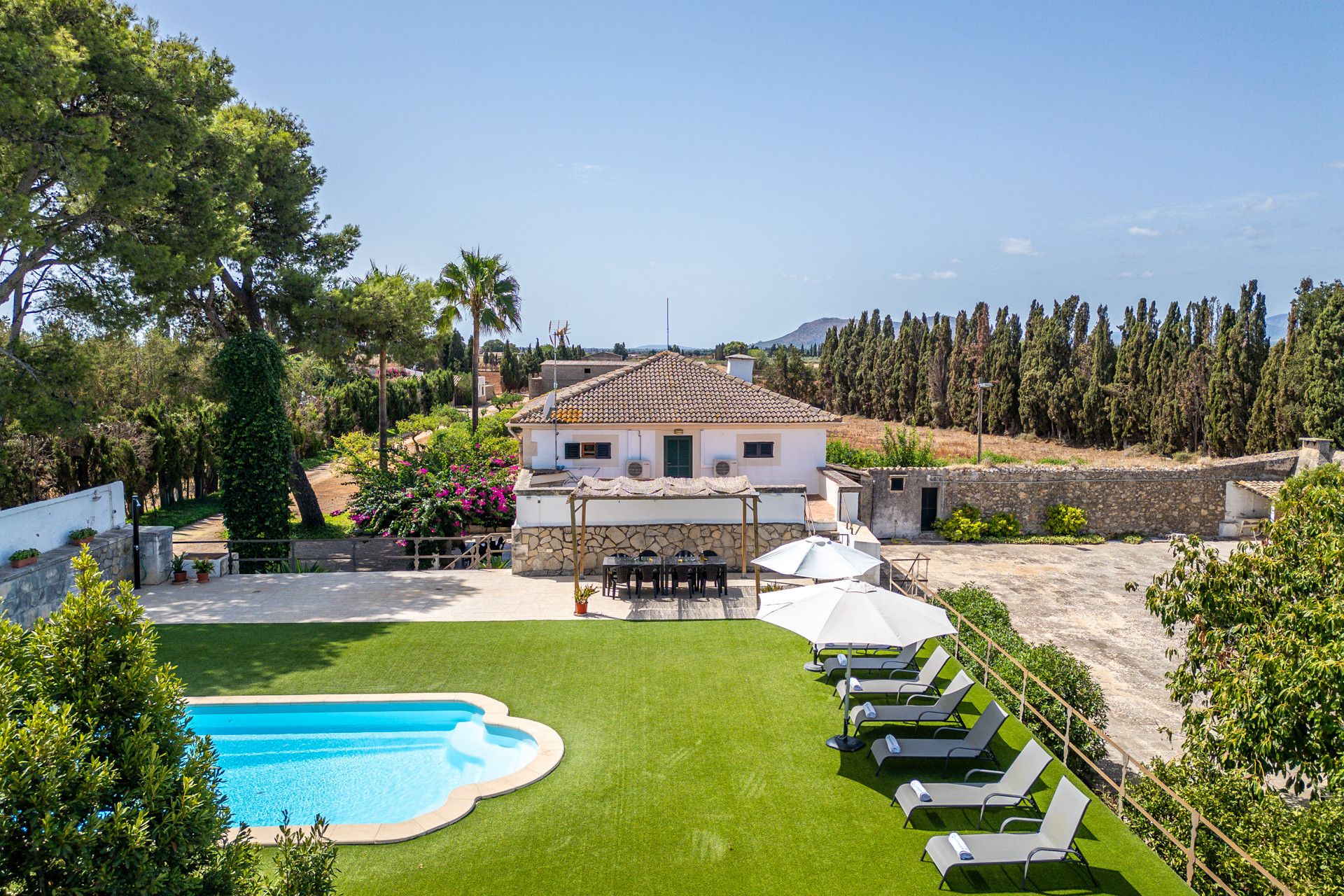 A villa with a swimming pool, outdoor seating, and a view of the surrounding landscape.