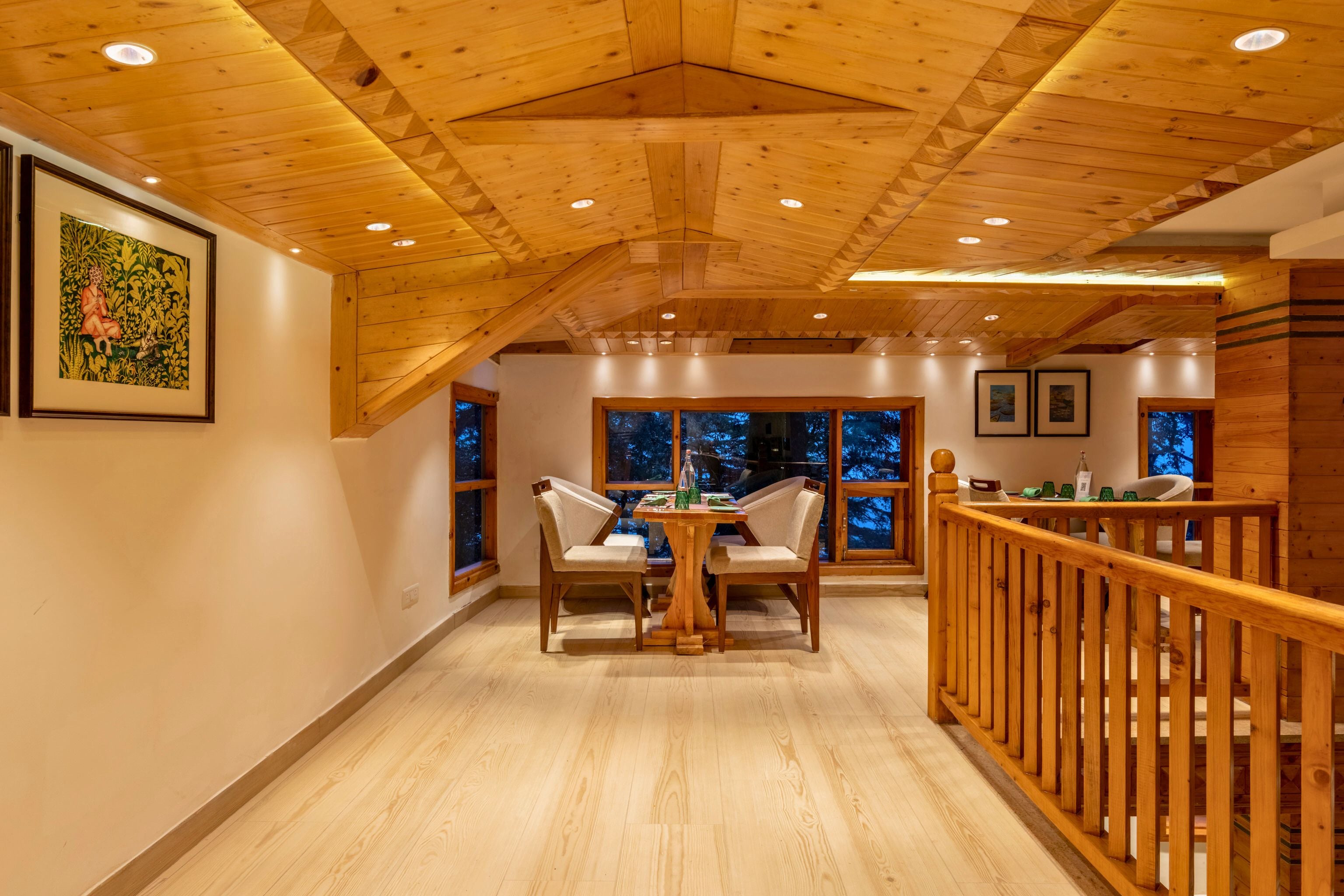 A wooden interior with a dining area, wooden ceiling, and large windows.
