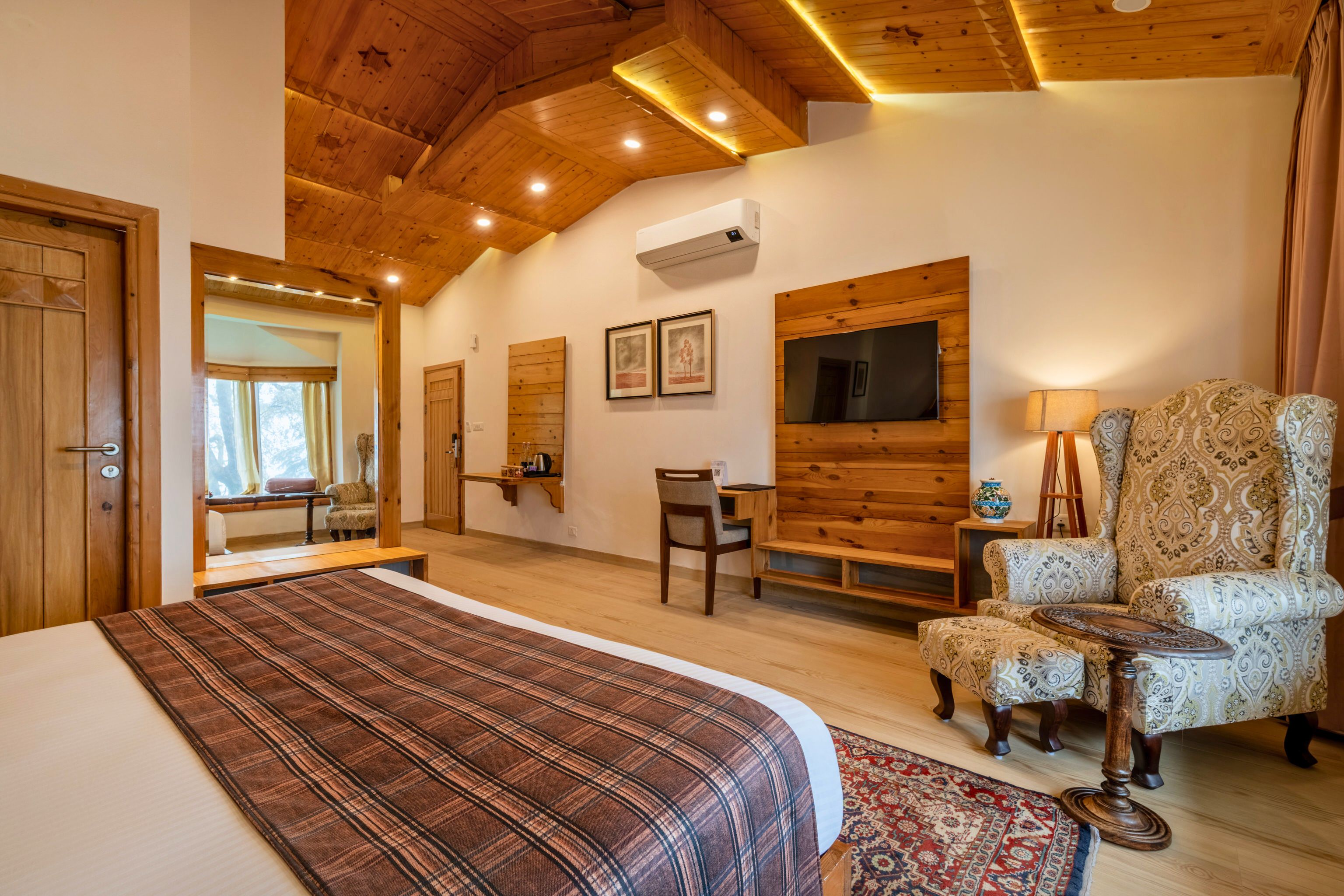 Quarto com cama, cadeira, escrivaninha e televisão.
