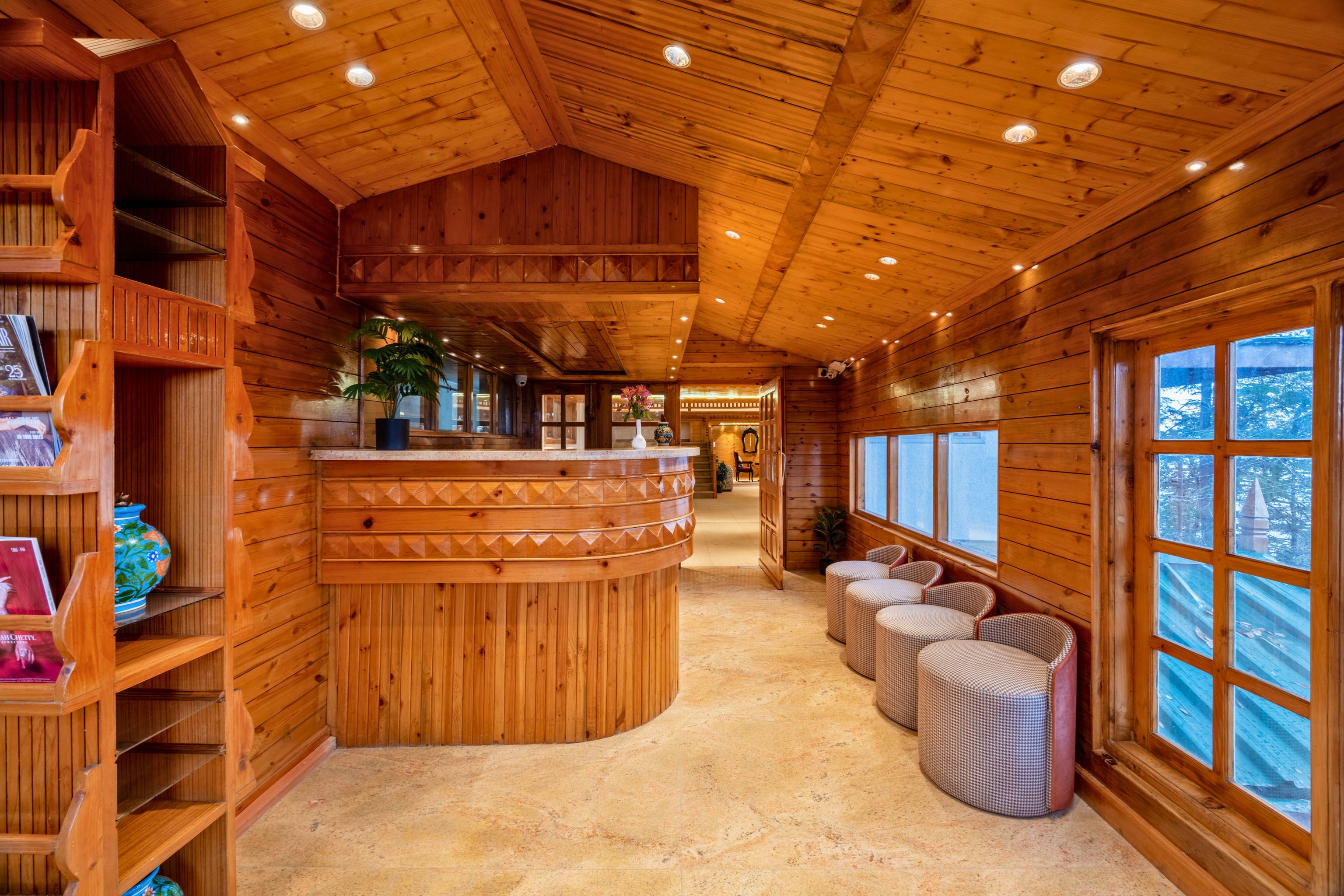 Ein Holzinterieur mit einer gebogenen Rezeption, einer Sitzecke und großen Fenstern.