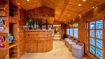 Ein Holzinterieur mit einer gebogenen Rezeption, einer Sitzecke und großen Fenstern.
