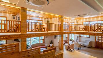 A multi-level wooden interior with a staircase, seating areas, and large windows.