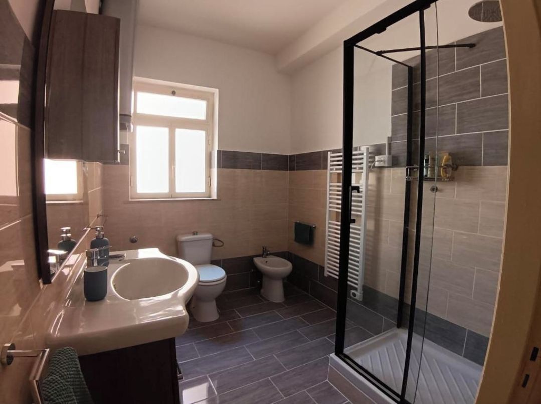 Une salle de bain avec une douche à parois de verre, un lavabo, des toilettes et un bidet.