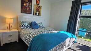 A bedroom with a bed, a bedside table with a lamp, and two paintings on the wall. - Mapua View! Surrounded by rolling pasture and manicured gardens (Richmond)
