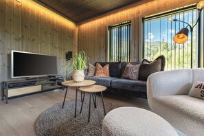 A modern living room with a flat-screen TV, a sofa set, a coffee table, and a large window with a view of the outdoors. - Mountain apartment in Hemsedal - For skiing and mountain tours (Hemsedal)