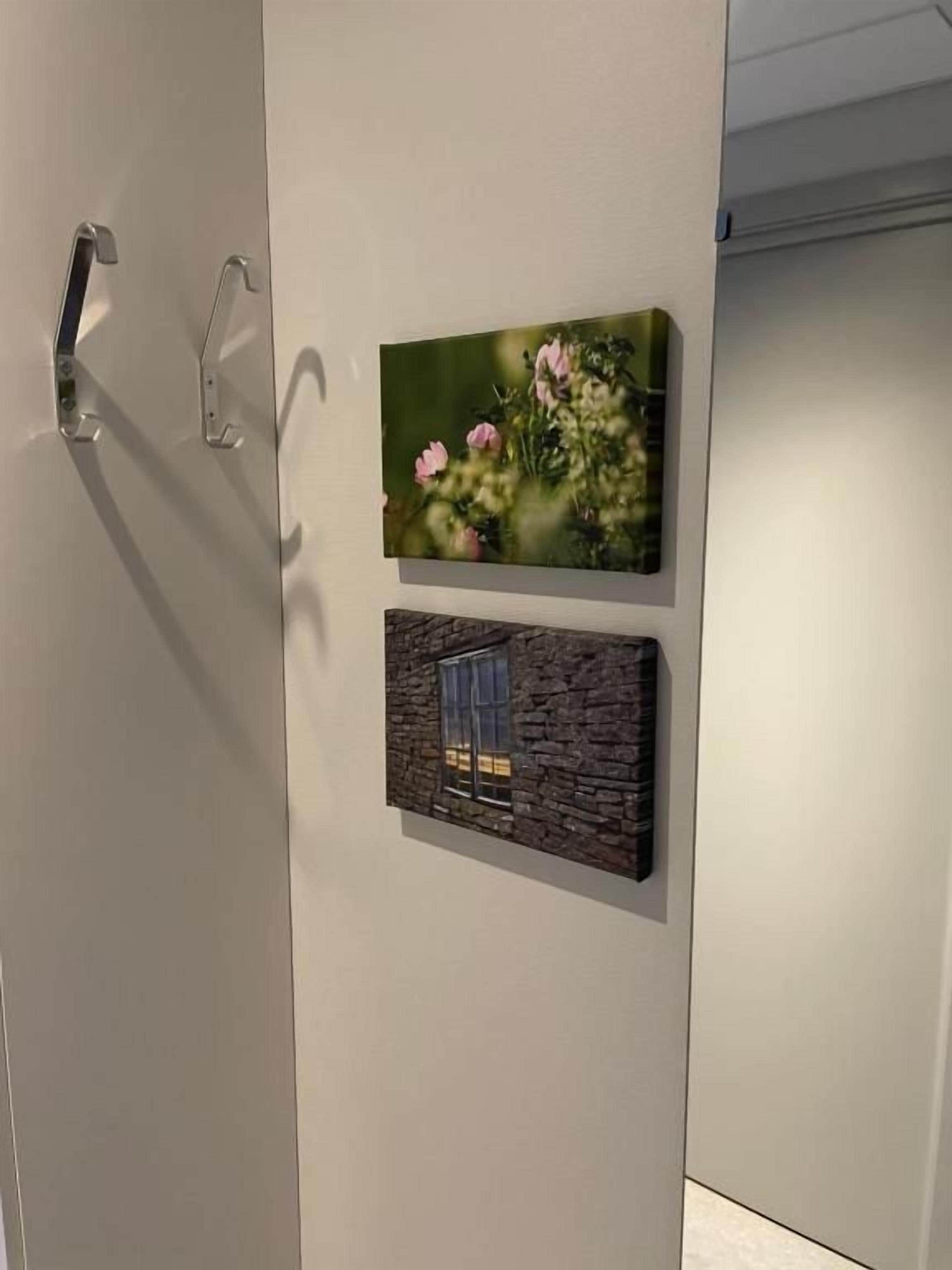 En vägg med två inramade konstverk; det ena föreställer blommor och det andra en byggnadsfasad.