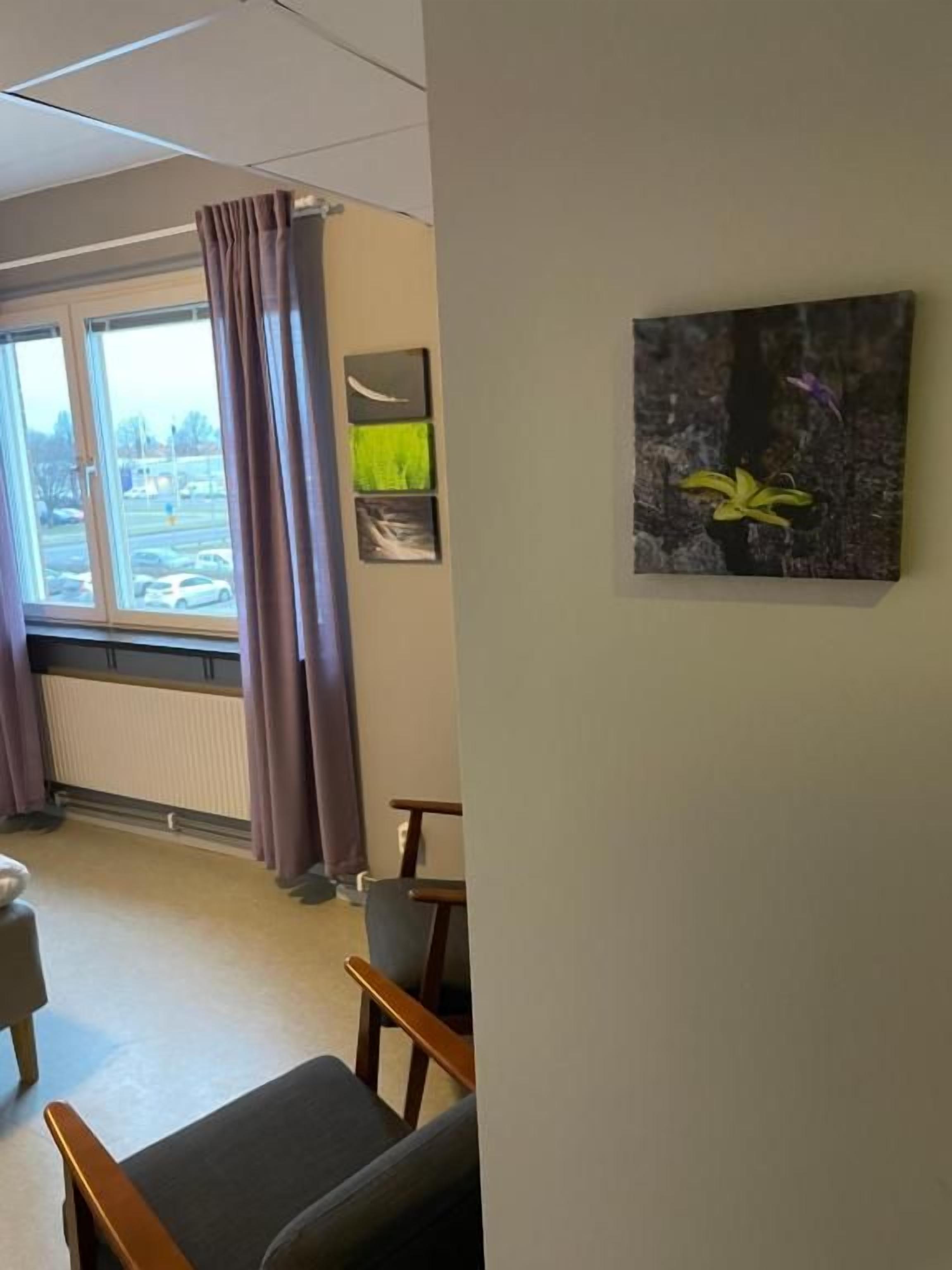 Una habitació amb finestra, una cadira, un taulell i un quadre a la paret.