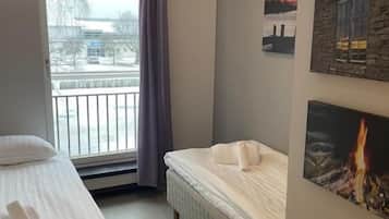 Una habitación de hotel con una cama, una silla, una ventana que ofrece vistas al exterior y una pared con un cuadro.