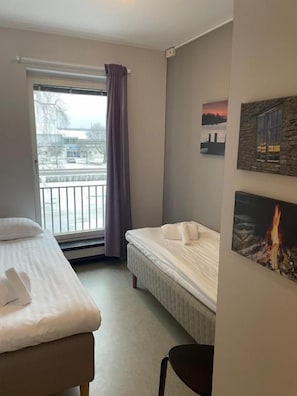 A hotel room with a bed, a chair, a window with a view of the outside, and a wall with a picture.