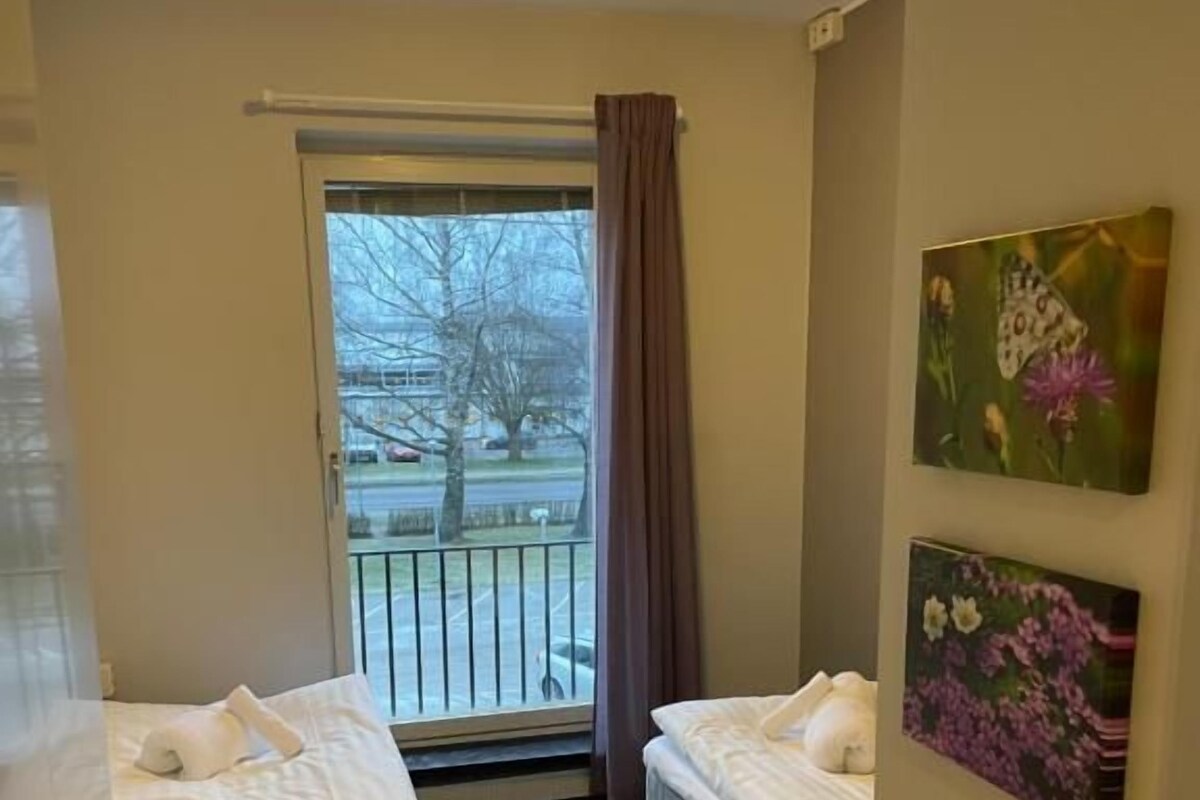 Habitaci ón de hotel con dos camas, una ventana con vistas al exterior y dos cuadros en la pared.