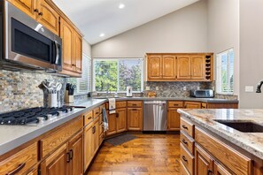 A modern kitchen with wooden cabinets, a stainless steel range, and a dishwasher. - Pool + Hot Tub + Gym | Near Village + Trails | Poolside Pines Reunion House (Lake Arrowhead)