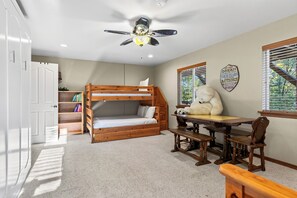 Ein Schlafzimmer mit Etagenbett, Schreibtisch und Deckenventilator.