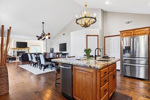 A spacious kitchen with a large island, wooden cabinets, stainless steel appliances, and a chandelier. - Pool + Hot Tub + Gym | Near Village + Trails | Poolside Pines Reunion House (Lake Arrowhead)