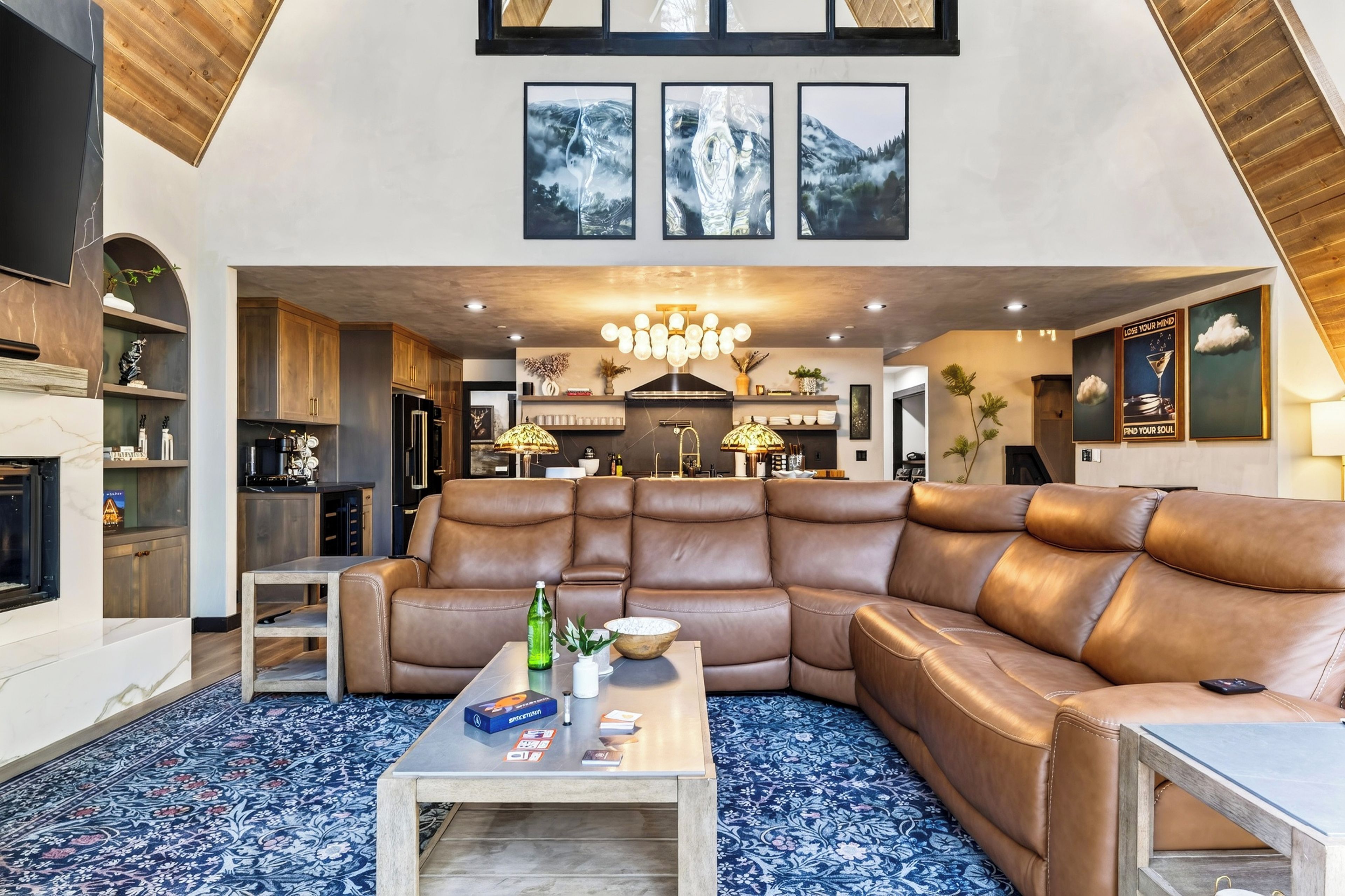 A spacious living room with a large leather sectional sofa, a coffee table, and a fireplace.