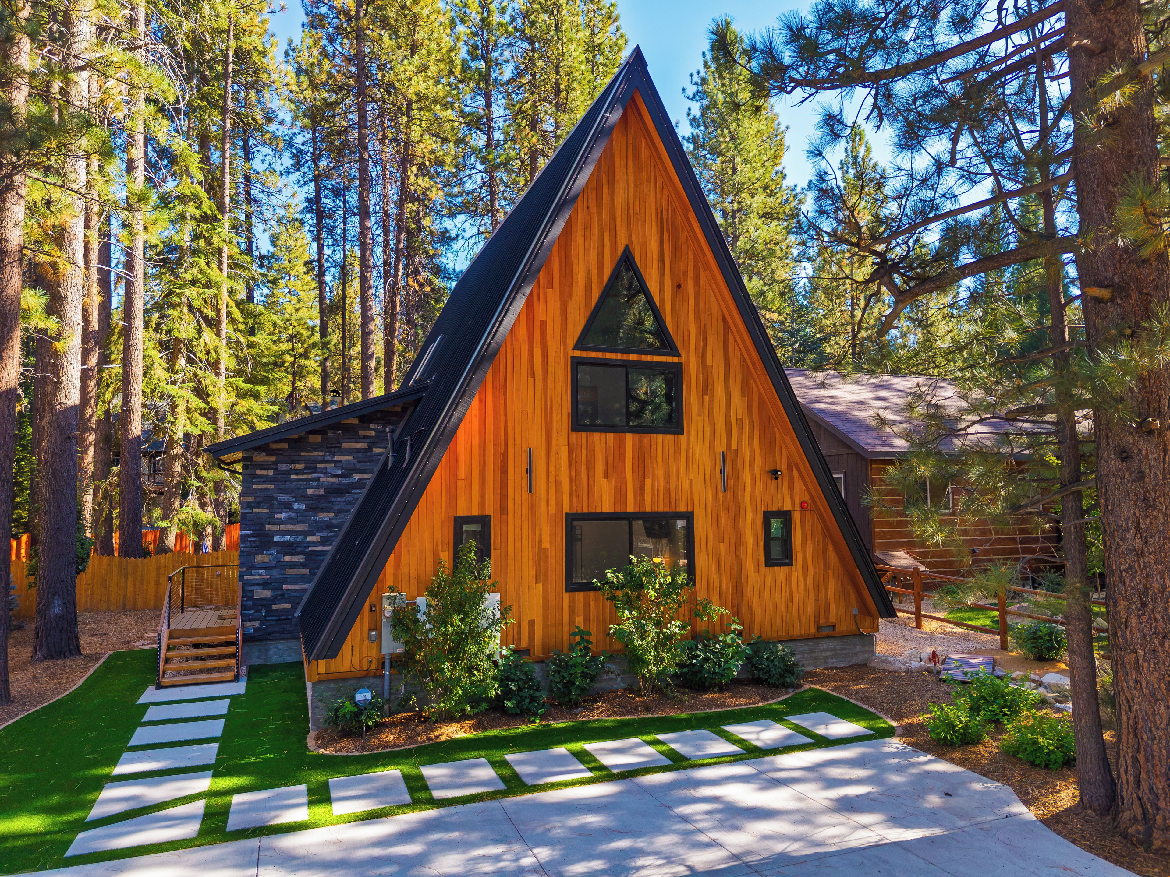 Une cabane dotée d’un toit triangulaire, entourée de grands pins.