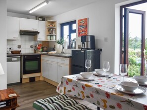 A modern kitchen with white cabinets, a black refrigerator, and a dining area with a table set for two. - 2 bedroom accommodation in Repps-with-Bastwick (Repps-with-Bastwick)