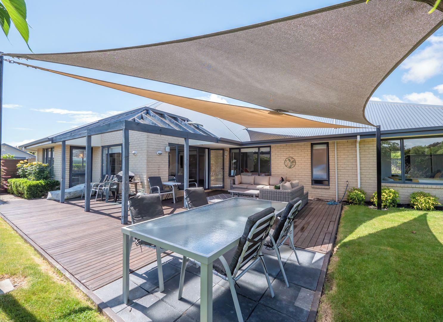 Une maison moderne dotée d’un patio, d’un espace salon extérieur et d’une zone abritée.