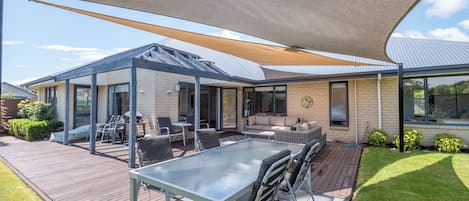 Une maison moderne dotée d’un patio, d’un espace salon extérieur et d’une zone abritée.