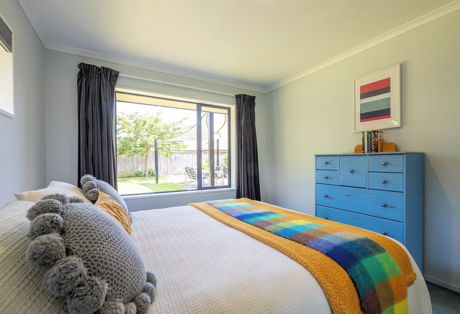 A bedroom with a large bed, a dresser, and a window with curtains.