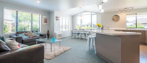 Uma sala de estar moderna com sofá, mesa de centro e área de jantar com cadeiras.