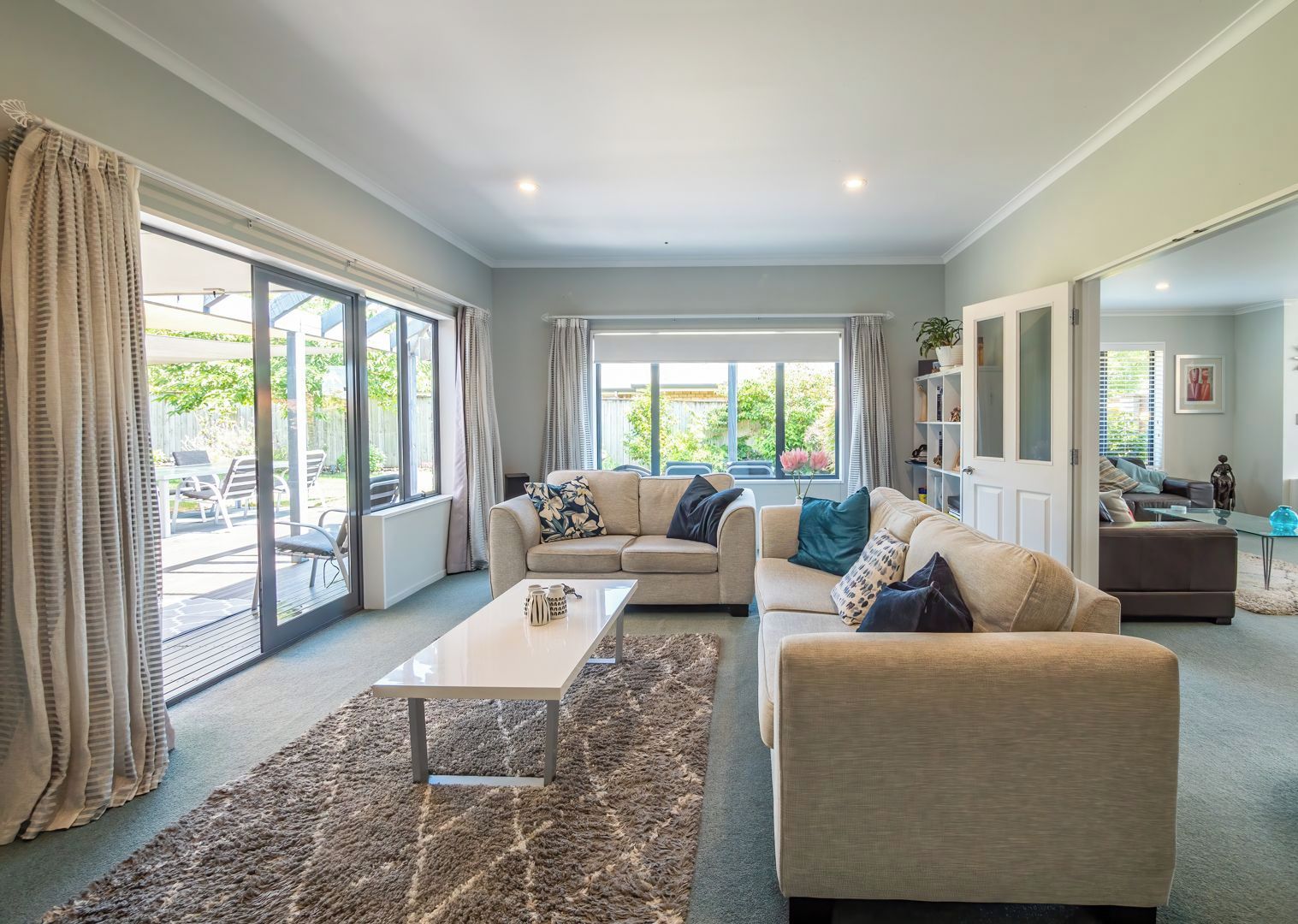 A spacious living room with a large window, a sofa set, a coffee table, and a rug.