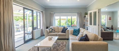 A spacious living room with a large window, a sofa set, a coffee table, and a rug.