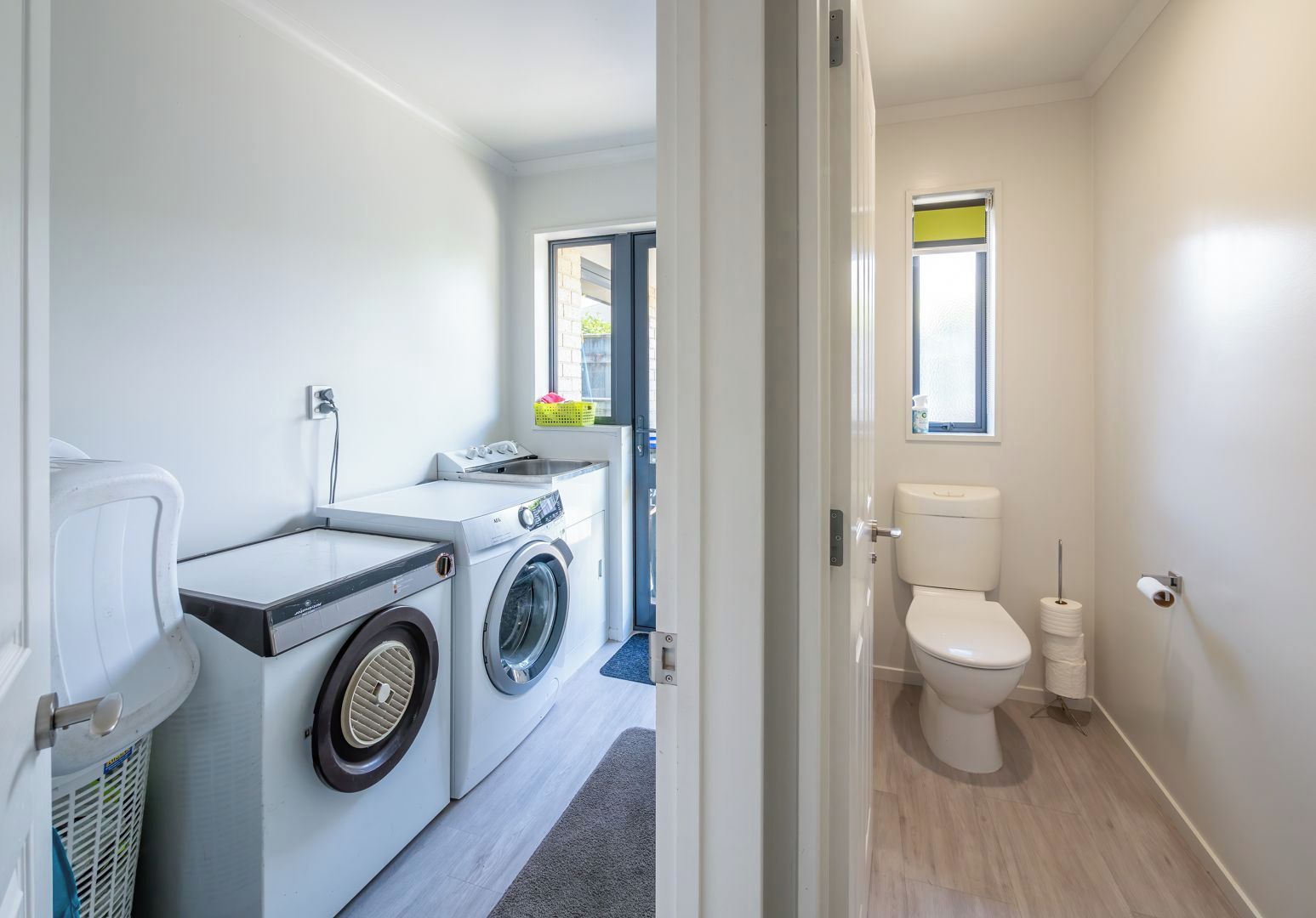 A compact laundry room with a washing machine, dryer, and a toilet.