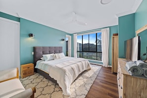 A bedroom with a large bed, a wooden nightstand, a dresser, and a window with a view of the outdoors. - Fletchers Ridge House (Montville)