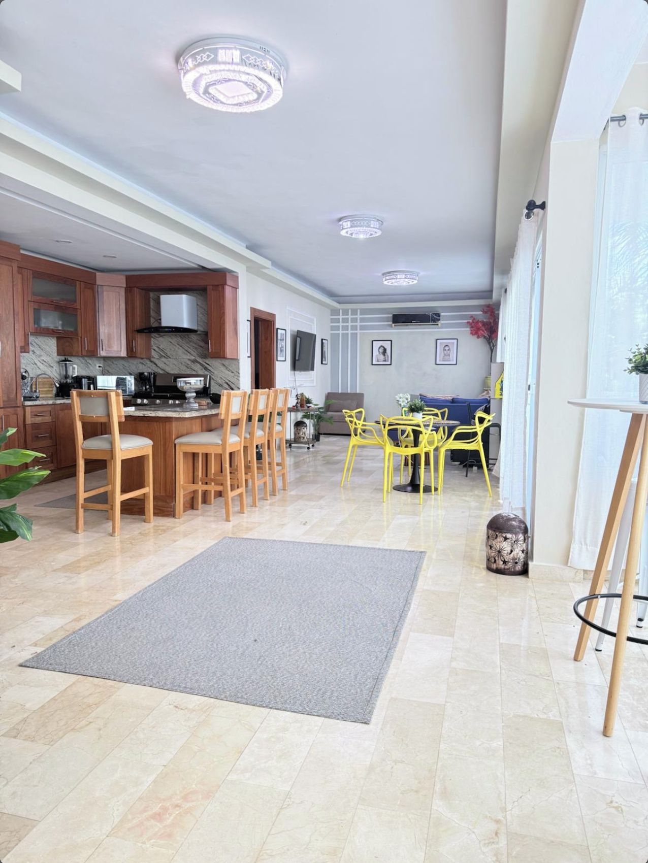 A spacious living area with a kitchen, dining area, and a seating space with yellow chairs.
