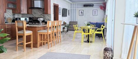 A spacious living area with a kitchen, dining area, and a seating space with yellow chairs.