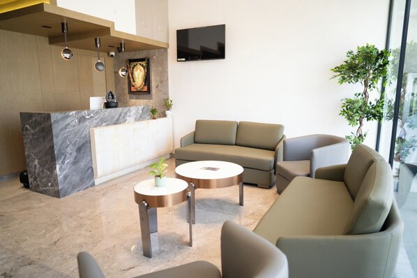 A modern lobby with a reception desk, seating area, and a large window.