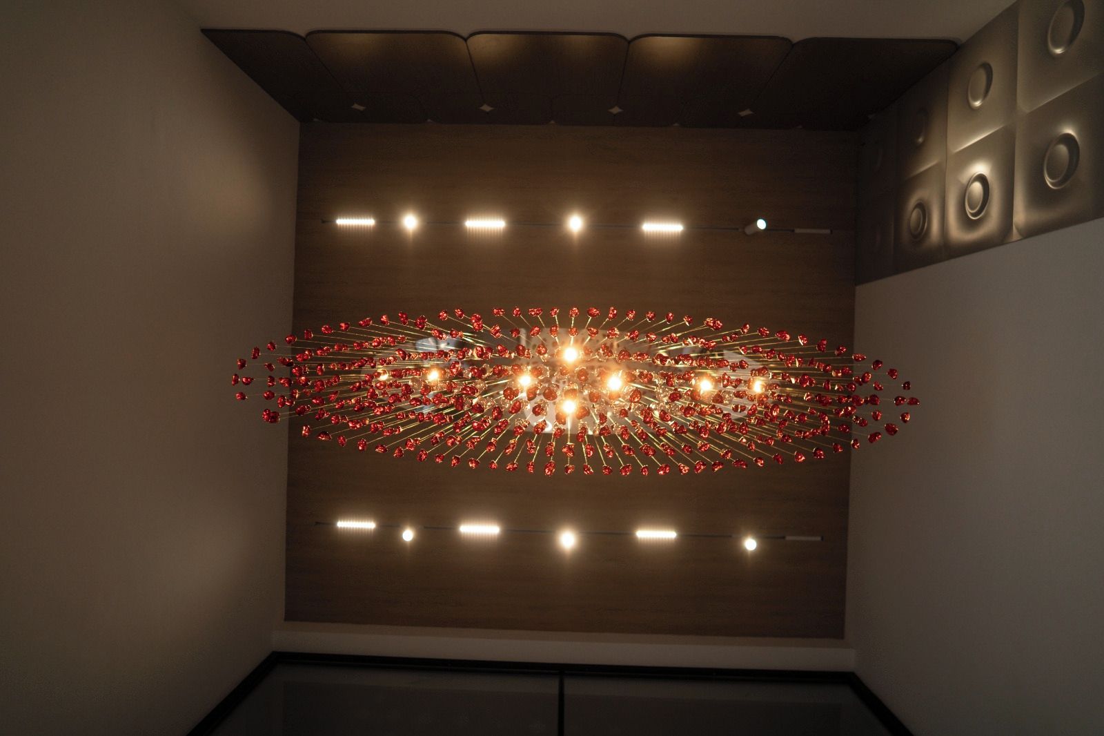 Un interior moderno con un diseño de techo único, que presenta una lámpara central rodeada de detalles rojos.