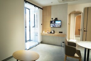 A modern kitchen with a flat-screen TV, a coffee machine, and a small counter.