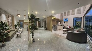 A modern hotel lobby with a reception desk, seating area, and a large window offering a view. - Hotel KPS inn (Karur)