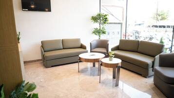 A modern living room with a sofa, two coffee tables, and a TV mounted on the wall.