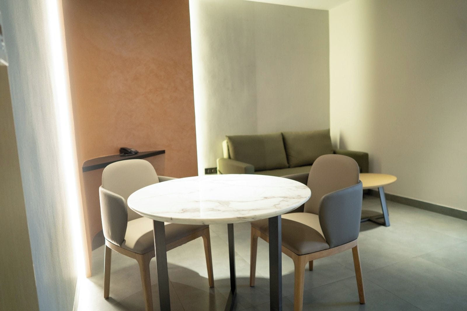 A modern room with a round table, four chairs, a sofa, and a small table.