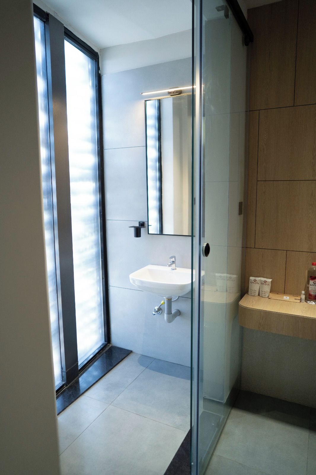 Un baño moderno con cabina de ducha de vidrio, un lavabo blanco y un espejo.