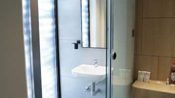 Un baño moderno con cabina de ducha de vidrio, un lavabo blanco y un espejo.