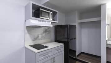 A compact kitchen with a microwave, refrigerator, and a small countertop.