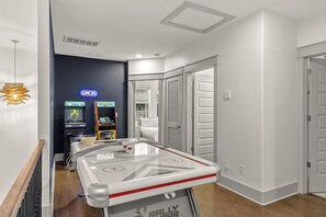 Quarto de hotel com mesa de bilhar, jogos eletrônicos e um letreiro neon.