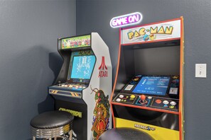 Two arcade machines, one labeled 'CENTIPEDE' and the other 'B-MAN,' with a neon 'GAME ON' sign above them. - Golf Cart + Arcade Game Room | Pool Access | 5 Min to Beach | Costal 45 (Miramar Beach)