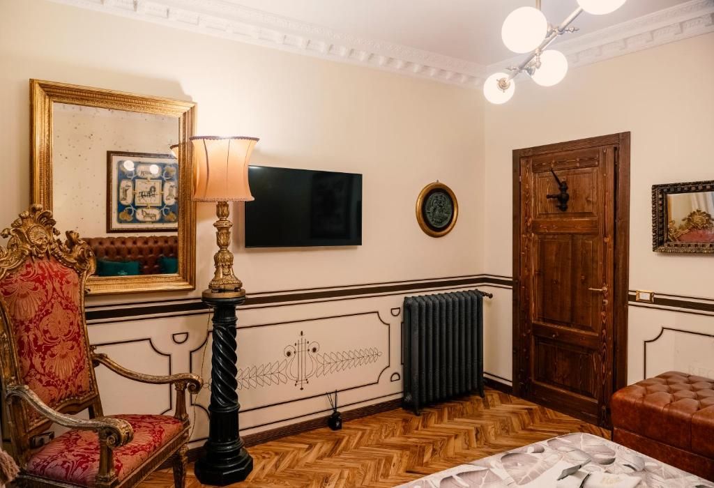 A room with a television, a wooden door, a radiator, a lamp, and a chair.