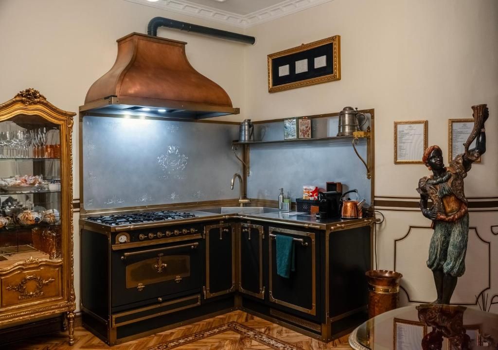 A kitchen with a stove, copper range hood, and a decorative statue.