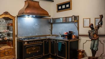 A kitchen with a stove, copper range hood, and a decorative statue.