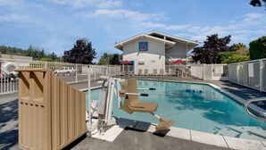 A pool area with a lifeguard chair, a wooden sauna, and a building with a '6' logo. - Sunny Queen Bed Room|Pool|Free Wifi (Bellingham)