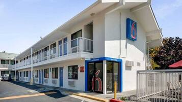 A motel with a blue entrance, a balcony on the second floor, and a parking lot.