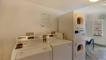 A laundry room with stacked washers and dryers, a fire alarm, and a notice board.