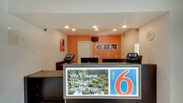 A motel reception desk with a large number '6' sign, a clock, and a digital display.